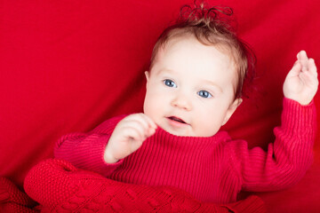 Little baby on red blanket in bed