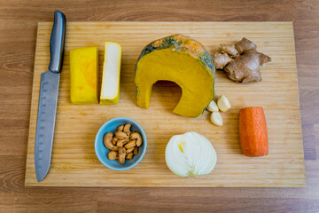 Cutting board with ingredients for preparing pumpkin porridge with tofu and vegetables