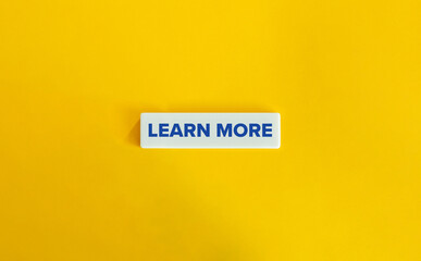 Learn More Phrase. Action Oriented Language and CTA Prompt. Blue Text on Block Letter Tile on Yellow Background. Minimal Aesthetic.