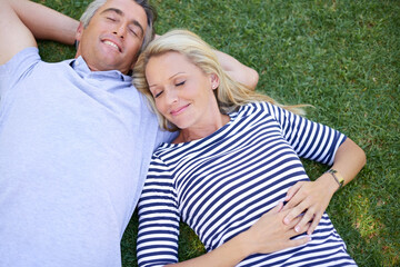 Relax, calm and couple on grass in park for romantic outdoor date with bonding and connection. Love, marriage and people laying for nap on green lawn in garden, nature or field from high angle.