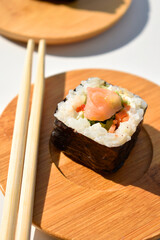 Sushi on a wooden plate on white surface