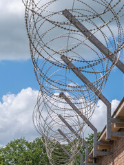 Barbed wire on the roof of a building against a background of blue sky with clouds
