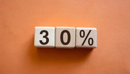 Wooden cubes with text 30% on orange backdrop. Wood blocks, number percent. Close-up. Flat lay