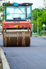 working people roll out new asphalt using special equipment on a hot summer day, arranging city streets and making life better for cars and drivers