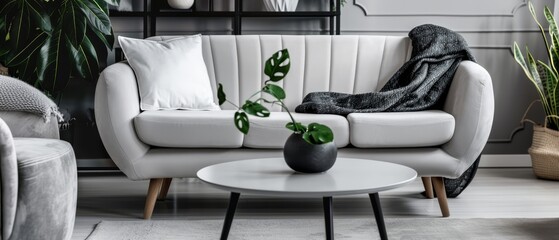  A white couch lies next to a table, bearing a potted plant atop it