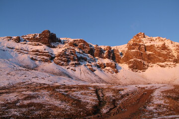 Snow-capped mountains and textured rock formations at sunset, creating a captivating scene for outdoor enthusiasts and nature lovers. Explore the beauty of nature in this stunning landscape setting.