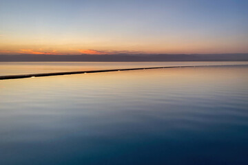 Obraz premium Sunset at Dead Sea looking form Jordan towards Israel with a swimming pool in the foreground