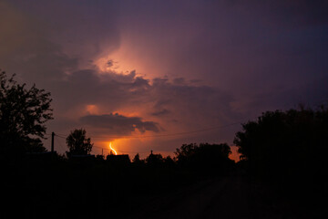 beautiful lightning during a thunderstorm at night in a forest that caused a fire, against a dark sky with rain