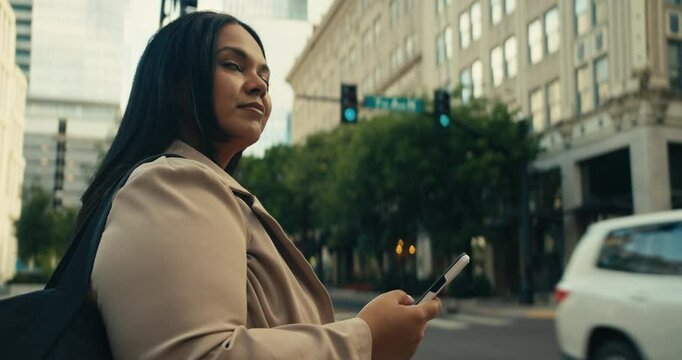 Young business woman walking around the city using her phone and laptop