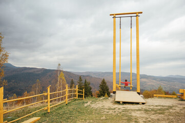 Boy in the mountains on a big swing