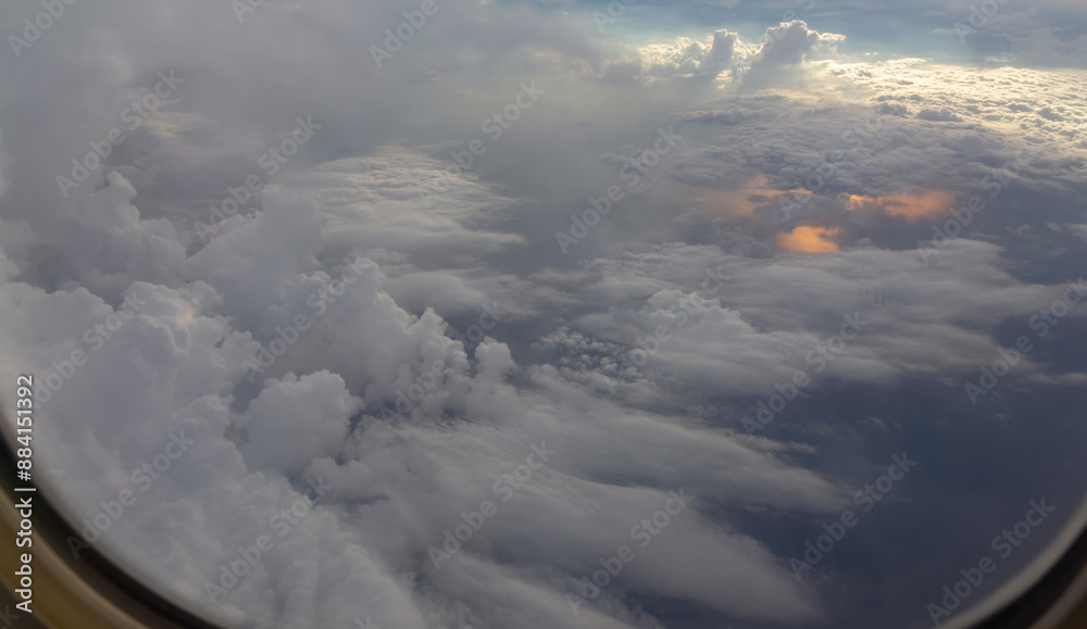 Poster the sky is filled with clouds and the sun is shining through them. thunderstorm from airplane window