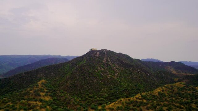 aerial drone orbiting shot of Savitri mata mother mandir temple on Aravalli mountain peak with ropeway going to it under cloudy sky in Pushkar Rajasthan
