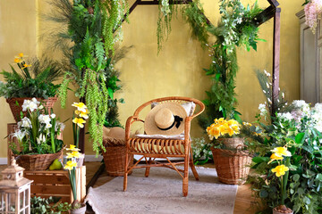 Wicker wooden chair with pillows and straw hat. Eco furniture, natural furniture.Concept Summer travel and vacation. Modern boho room with interior design, rattan chair and green plants in baskets.	
