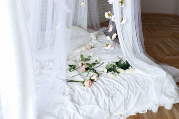 Roses on bed in room. Bedroom interior design. Closeup of bed with scattered pink and white roses. Bed with flowing curtains and garland flowers levitating, hanging flowers. Honeymoon. Valentine day   © stock_studio
