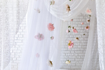 Baldachin on bed. Summer pink peonies and roses flowers levitating, hanging flowers, copy space. Template, mockup. White lace curtains canopy with floral abstract pattern with spring flowers levitate	