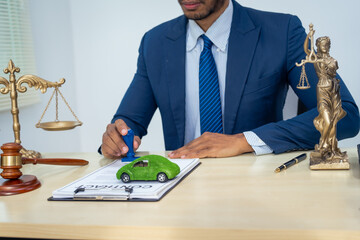 An Asian businessman in a formal suit works alone at a lawyer's desk, with golden scales, law...