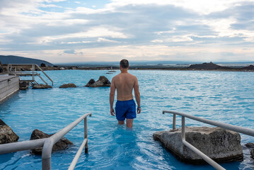 Man relaxing in the blue waters of a geothermal lagoon in Iceland