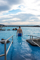 Fototapeta premium Man relaxing in the blue waters of a geothermal lagoon in Iceland