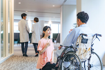 病院で車椅子の患者と会話する看護師