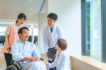 車椅子のシニア男性患者と会話する医師・看護師