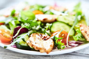 Salad with Chicken Breast, Cherry Tomatoes, Cucumber, Rocket and fresh Basil. Bright wooden background. Close up.	