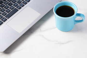 コーヒーを飲みながらノートパソコンでデスクワークをしているイメージ
