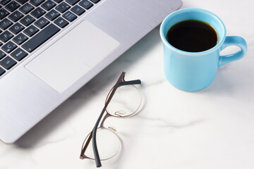 コーヒーを飲みながらノートパソコンでデスクワークをしているイメージ
