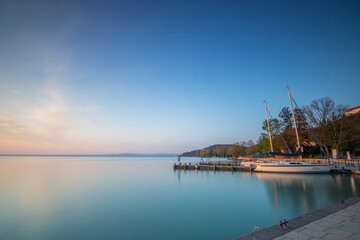 Sunrise on the shore and harbor of a lake in summer. Colorful sky with a wide view of the Horiont....