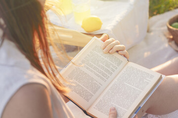 A woman finds peace and relaxation in nature while reading a book outdoors on a sunny day