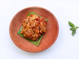 eggplant chili sauce, accompaniment to spicy food. fresh and hot traditional side dish. chili sauce made from eggplant served on a wooden plate against white background

