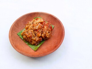 eggplant chili sauce, accompaniment to spicy food. fresh and hot traditional side dish. chili sauce made from eggplant served on a wooden plate against white background
