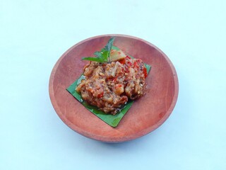 eggplant chili sauce, accompaniment to spicy food. fresh and hot traditional side dish. chili sauce made from eggplant served on a wooden plate against white background
