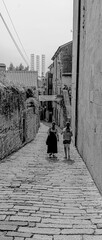 Mediterranean alley with two women walking down the hill in black and white