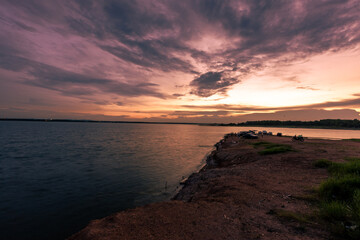 Obraz premium The background of the sea by the evening sea, with natural beauty (sea water, rocks, sky) and fishermen are fishing by the river bank, is a pleasure during travel.