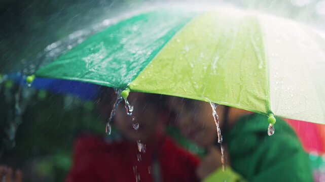 Happy preschool children boys hiding under umbrella,heavy rain.Kids in raincoats