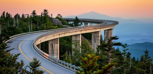 A concrete road that curves down a hillside with a sunset in the background