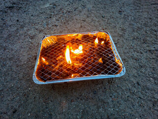 Lighting the disposable grill on the ground.