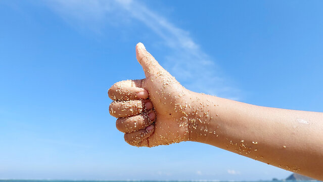Thumb up hand sign isolated on blue sky background.