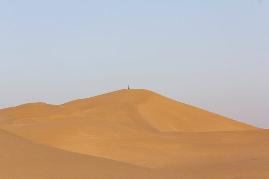 A man standing on top of a dune by himself indicating the concept of singlehood and loneliness.