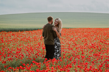 Young couple on romantic walk in poppy field 