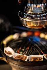 a close-up view of meat being grilled on a pan over an open flame