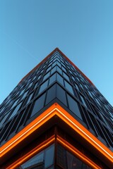 a corner of a tall building with a blue sky, orange neon light on the bottom edge of the frame