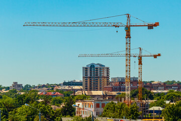Naklejka premium Construction cranes and cityscape of Kharkiv city on a sunny summer day