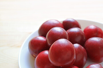 Heap of Fresh Dwarf Gulf Ruby Plum Fruits in a White Plate