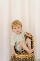 little boy sitting on a  wicker chair © Corin