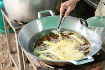 Cooking fried bananas in hot oil at a Thai street food stall.
