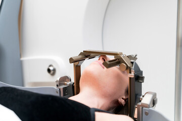 The patient lies in front of the device for the treatment of cancer with a gamma knife. She has a...