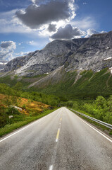 Fototapeta premium Road, mountains and landscape for travel, journey and tourism with snow melting for start of spring. Environment, nature and secluded street for getaway, transport and holiday or vacation in Norway