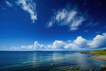 Fototapeta premium Vast blue sky with clouds over a calm coastline, ideal for serene backdrops
