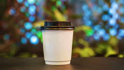 disposable cup for coffee or tea in cafe. Hot coffee in white paper cup isolated on wood table background. Blank paper cup of coffee in a coffee shop for the application logo. coffe paper cup bean